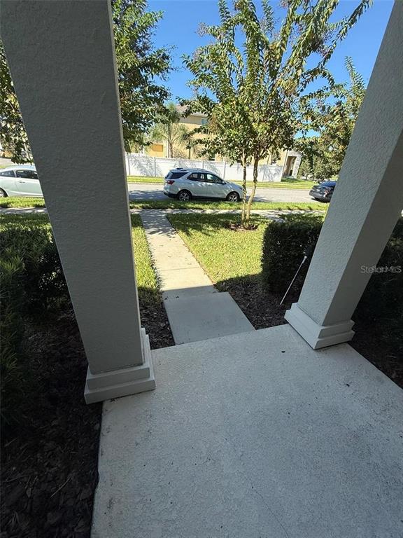 A view from a covered porch looking out toward a sidewalk, lawn, and parked cars — 11019 BOOKMARK LANE, WINTER GARDEN, FL