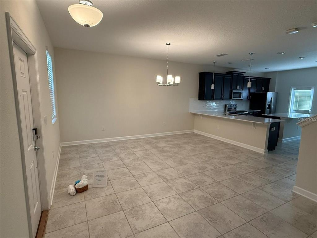 An open-concept dining area features light tile flooring, a chandelier, and an adjacent kitchen — 11019 BOOKMARK LANE, WINTER GARDEN, FL