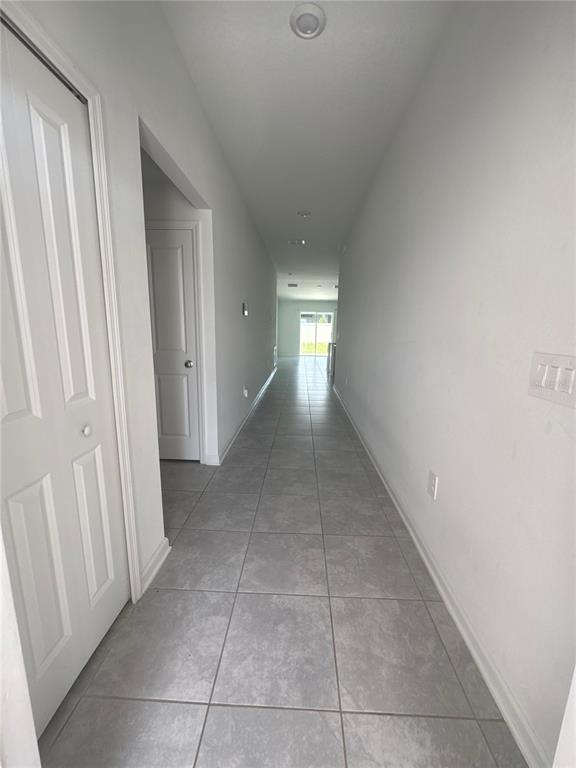 A long, narrow hallway features light gray tile flooring and white walls — 4269 NIGHT CAPS WAY, KISSIMMEE, FL