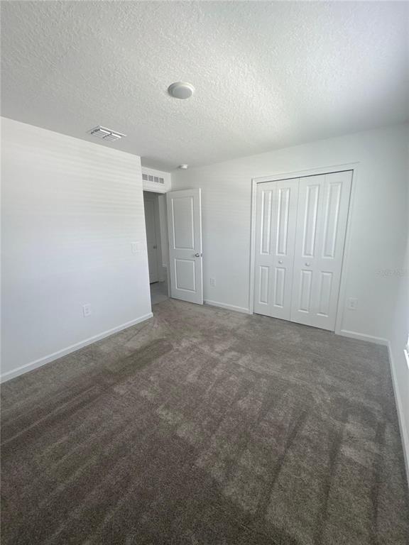 A bedroom with gray carpet, white walls, a closet with double doors, and a doorway — 4269 NIGHT CAPS WAY, KISSIMMEE, FL
