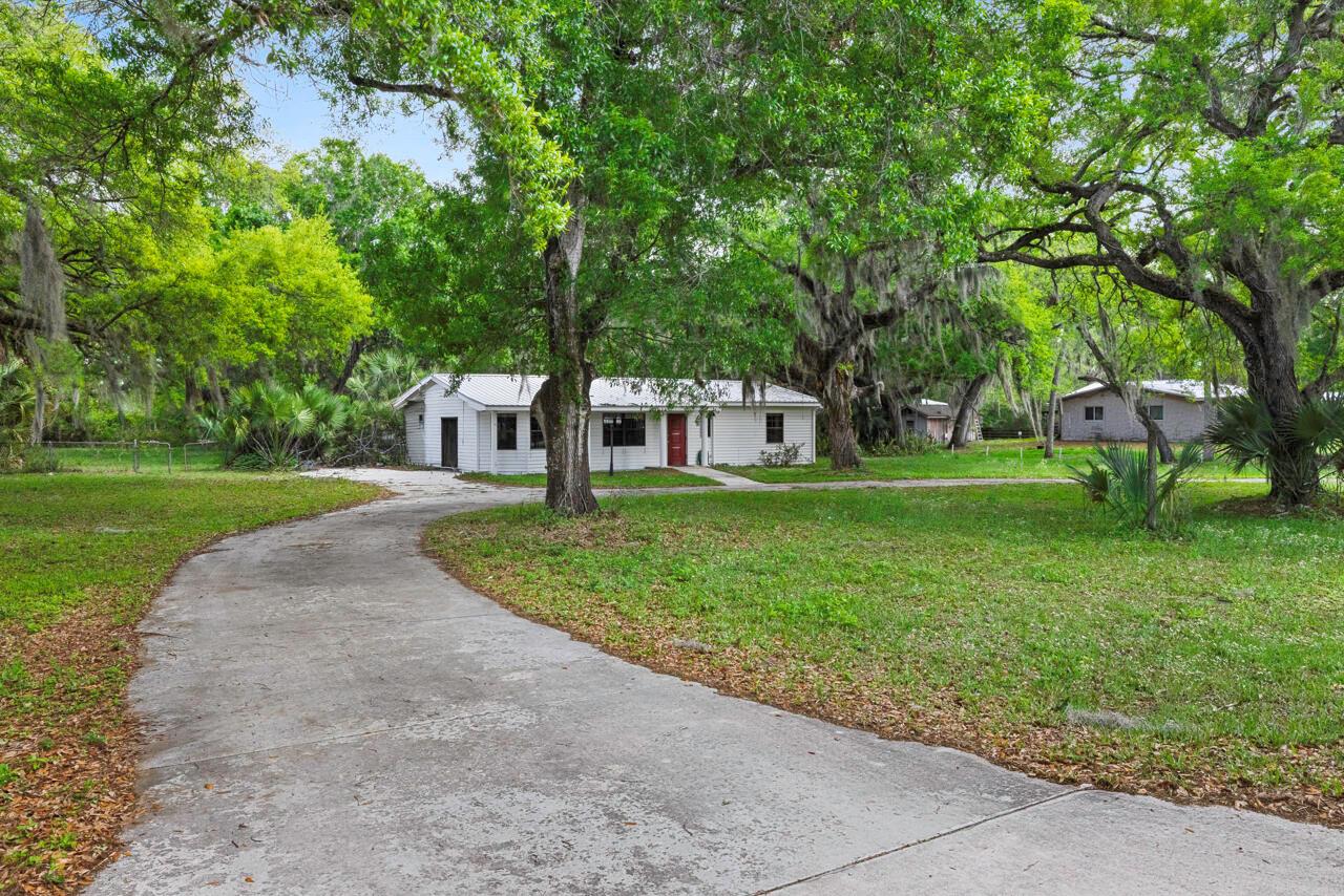 A white single-story house with a red door sits at the end of a driveway — 536 SE 16th Avenue, Okeechobee FL 34974, OKEECHOBEE, FL