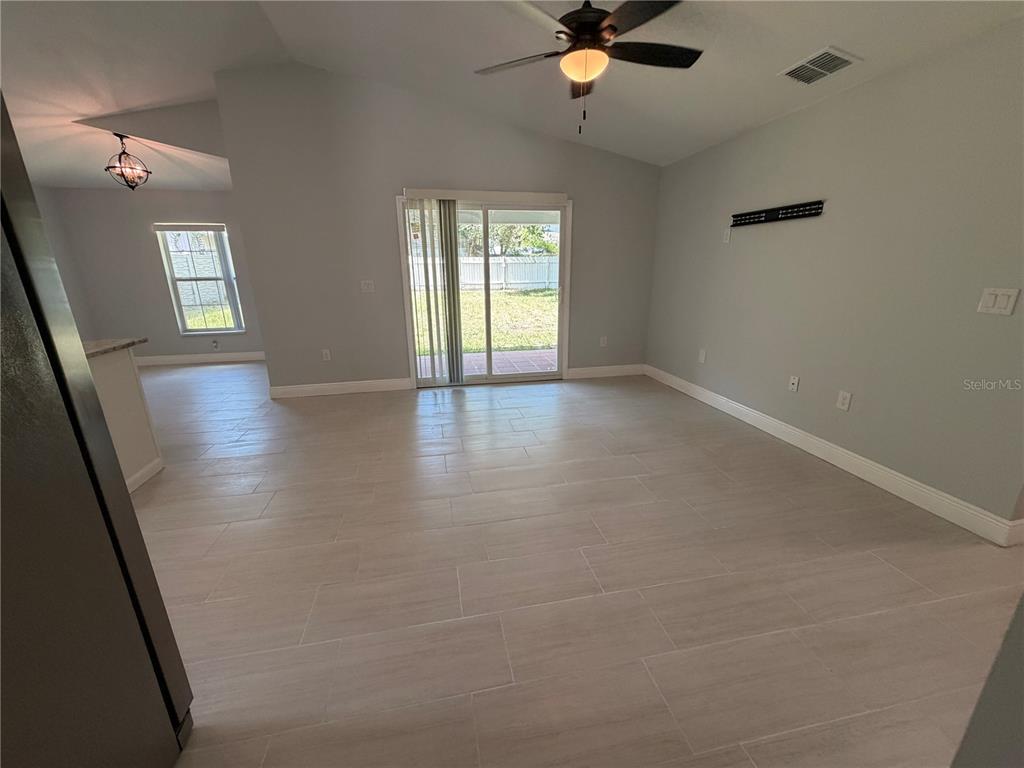 A living room features light gray walls, tile flooring, a ceiling fan, and sliding glass doors — 319 AVENUE A NE, WINTER HAVEN, FL