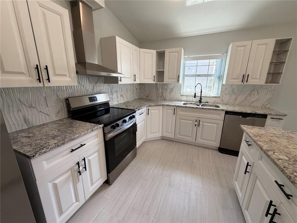 A kitchen with white cabinets, granite countertops, a stainless steel stove, and a tile floor — 319 AVENUE A NE, WINTER HAVEN, FL