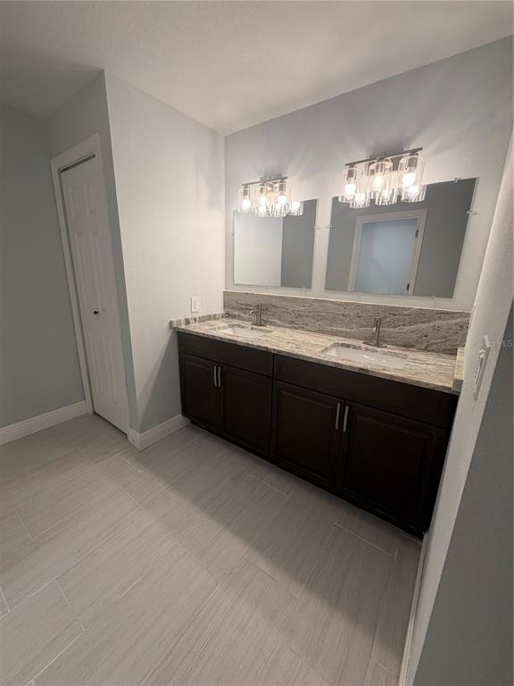 A bathroom features a double vanity with dark cabinets, stone countertops, and two wall-mounted mirrors — 319 AVENUE A NE, WINTER HAVEN, FL