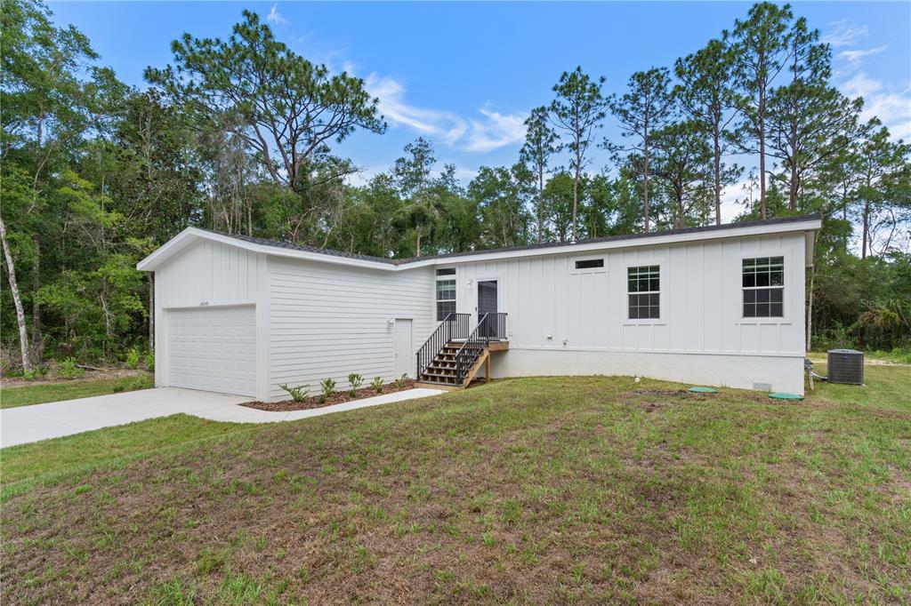 A white single-story house with a garage and stairs leading to the front entrance — 14249 E RAZORBILL AVENUE, WEEKI WACHEE, FL