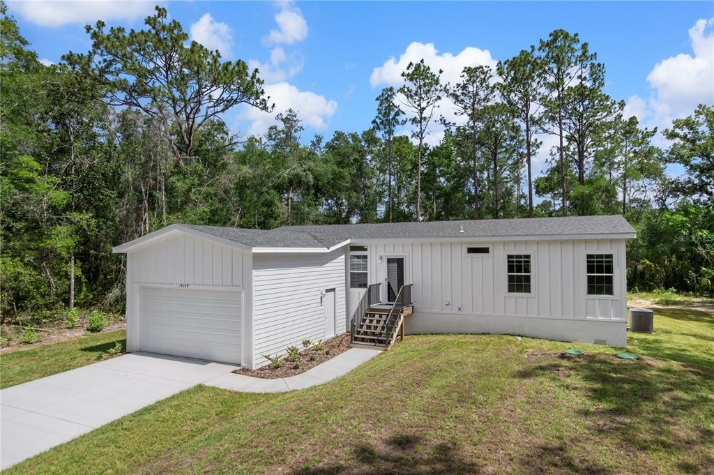 A white, single-story house with a garage and a front staircase sits on a lawn — 14249 E RAZORBILL AVENUE, WEEKI WACHEE, FL