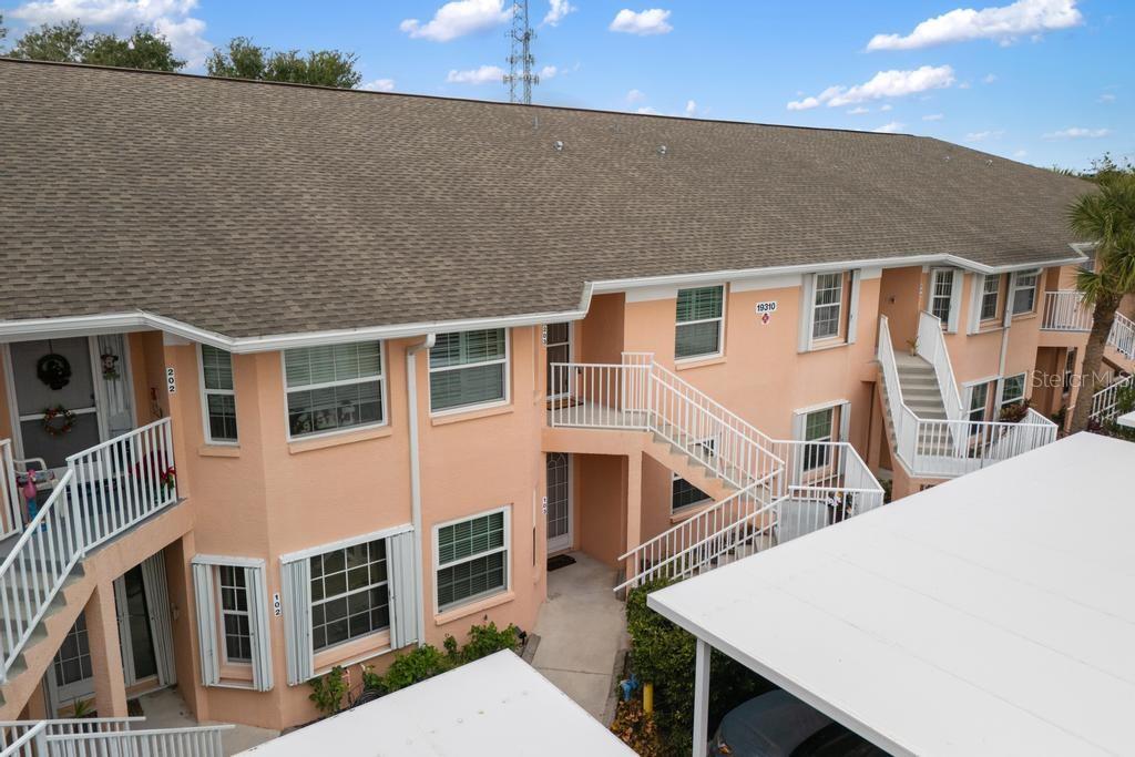 An exterior view of a two-story peach-colored apartment building with white railings and stairs — 19310 WATER OAK DRIVE UNIT 103, PORT CHARLOTTE, FL