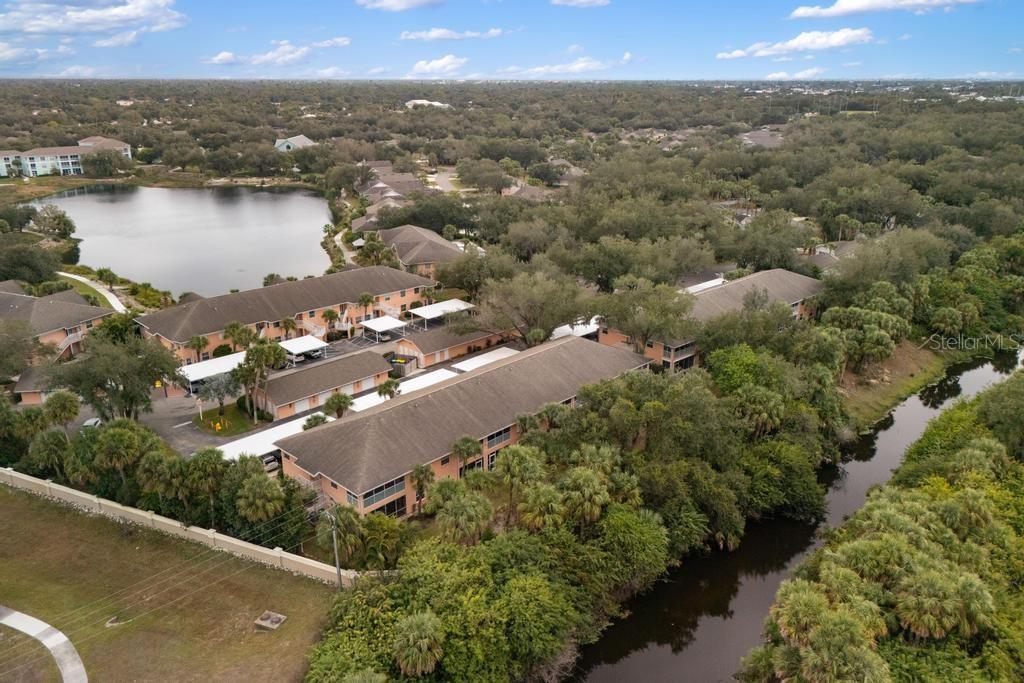 An aerial view shows multi-story apartment buildings situated near a lake and a canal — 19310 WATER OAK DRIVE UNIT 103, PORT CHARLOTTE, FL