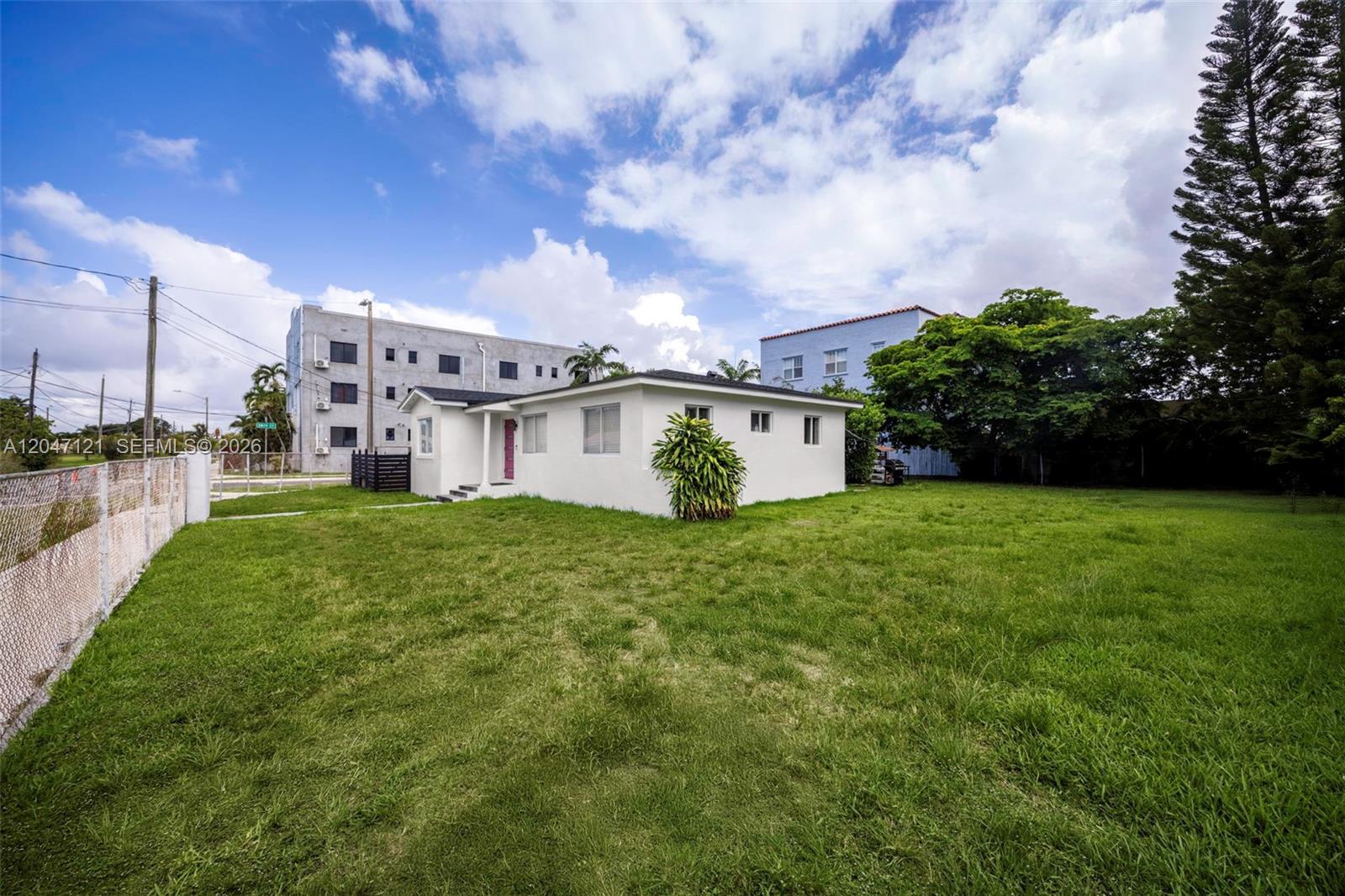 A white single-story house sits on a large grassy lot under a cloudy blue sky — 2939 SW 5th St, Miami FL 33135, MIAMI, FL