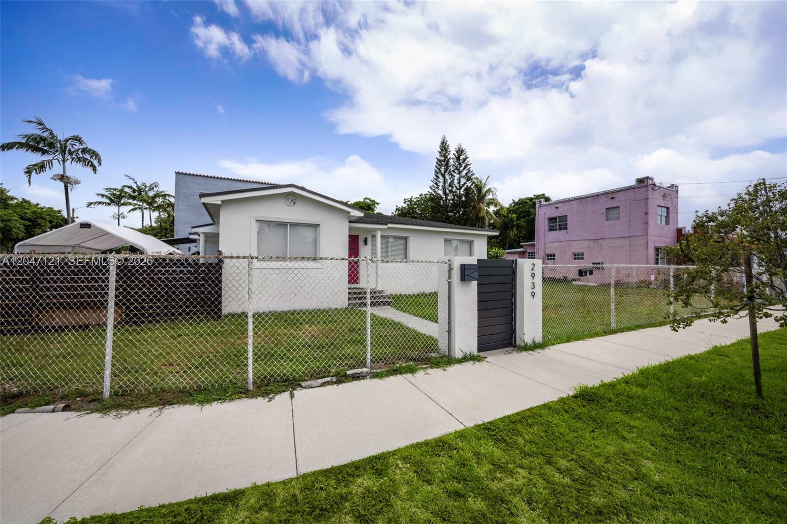 A white house with a pink door is enclosed by a chain-link fence — 2939 SW 5th St, Miami FL 33135, MIAMI, FL