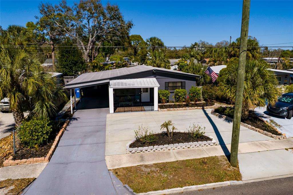An exterior view of a single-story house with a carport, concrete driveway, and landscaping — 8029 22ND AVENUE N, ST PETERSBURG, FL