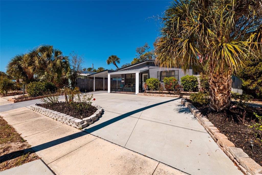 A single-story house with a concrete driveway, a carport, and palm trees in the yard — 8029 22ND AVENUE N, ST PETERSBURG, FL