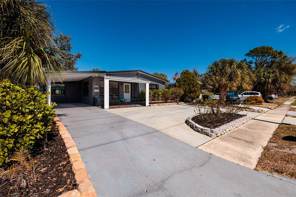 A single-story gray house features a carport, a concrete driveway, and a small front garden — 8029 22ND AVENUE N, ST PETERSBURG, FL