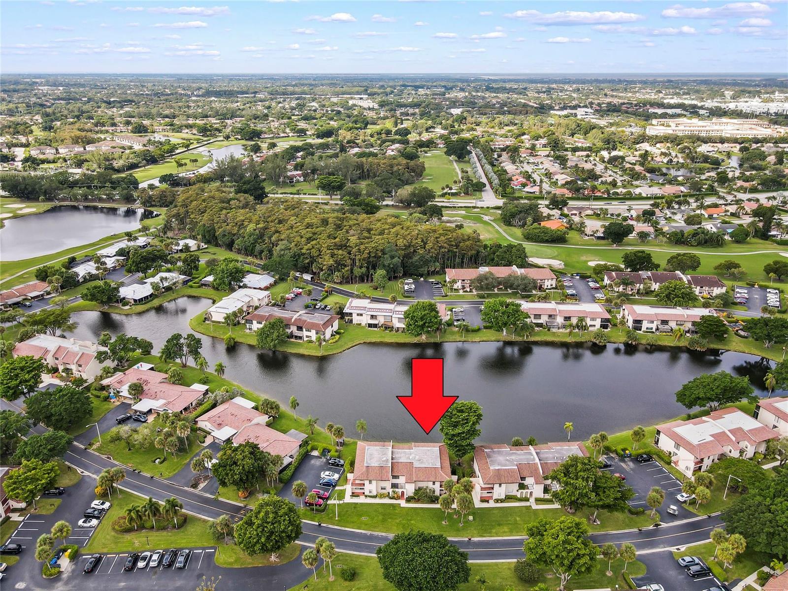 An aerial view shows multi-story residential buildings situated along a lake in a suburban area — 21649 Juego Circle, Boca Raton FL 33433, BOCA RATON, FL