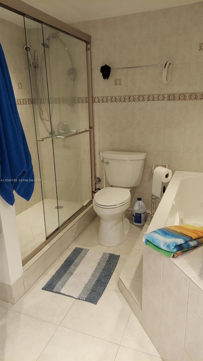 A bathroom features a glass-enclosed shower, a white toilet, and a tiled bathtub surround — 3140 S Ocean Dr # 1510, Hallandale Beach FL 33009, HALLANDALE BEACH, FL
