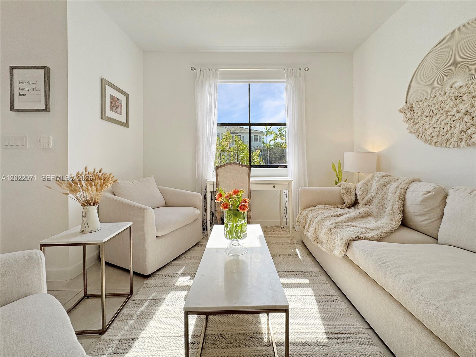 A bright living room features a sofa, armchair, coffee table, and a window with curtains — 14813 SW 183rd Ter # 14813, Miami FL 33187, MIAMI, FL