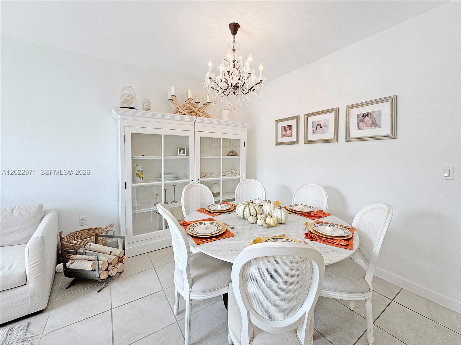 A dining room features a round marble table, white chairs, a crystal chandelier, and a hutch — 14813 SW 183rd Ter # 14813, Miami FL 33187, MIAMI, FL