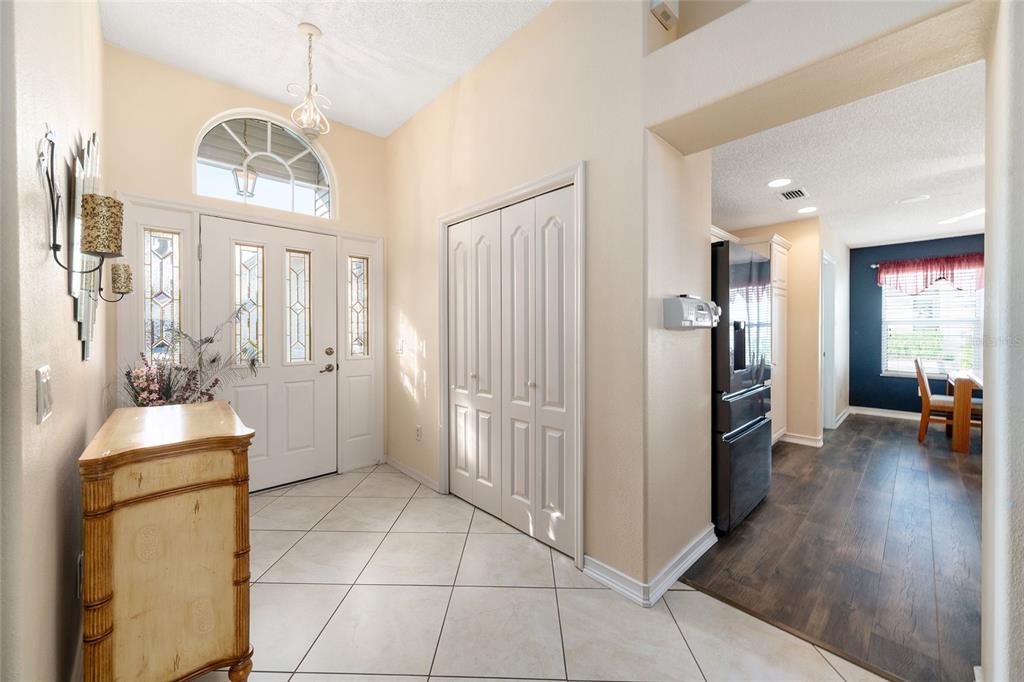 An entryway with tile flooring, a double-door closet, and a view into a kitchen area — 1529 STRATON WAY, THE VILLAGES, FL