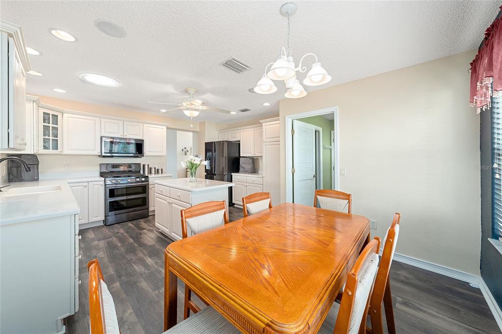 A kitchen with white cabinets, a central island, and a wooden dining table — 1529 STRATON WAY, THE VILLAGES, FL