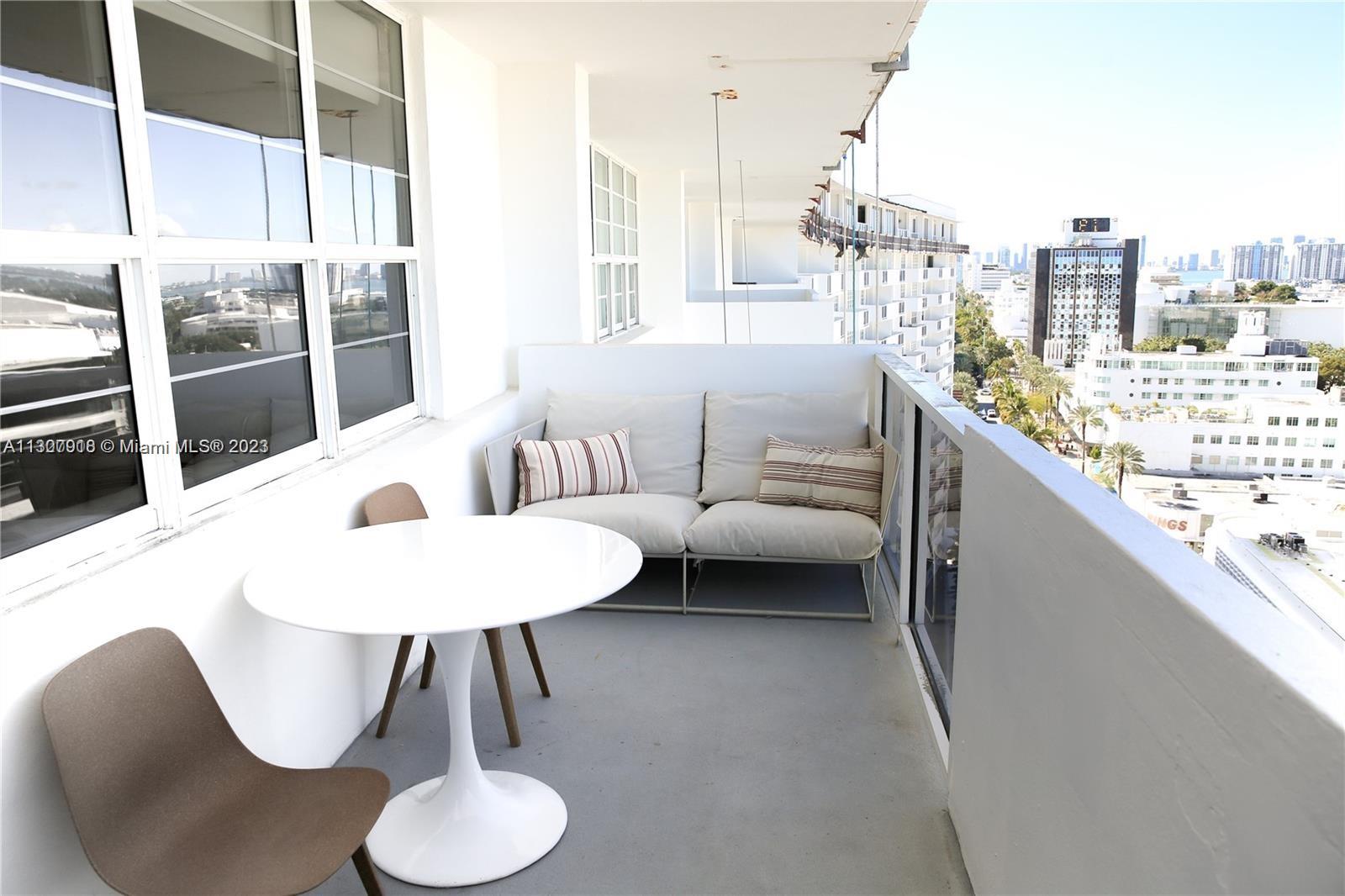 A balcony features a white round table, two chairs, and a sofa overlooking a city — 100 Lincoln Rd # 1643, Miami Beach FL 33139, MIAMI BEACH, FL