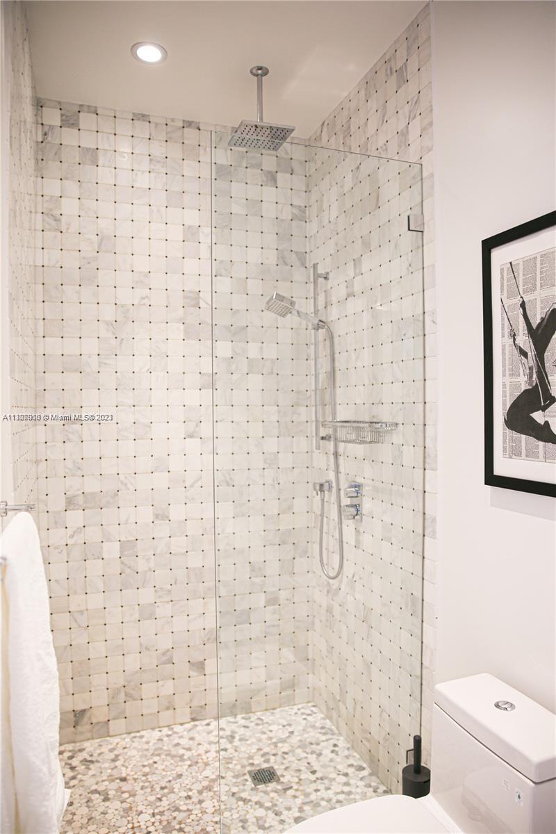 A bathroom features a glass-enclosed shower with marble tile walls and a pebble floor — 100 Lincoln Rd # 1643, Miami Beach FL 33139, MIAMI BEACH, FL