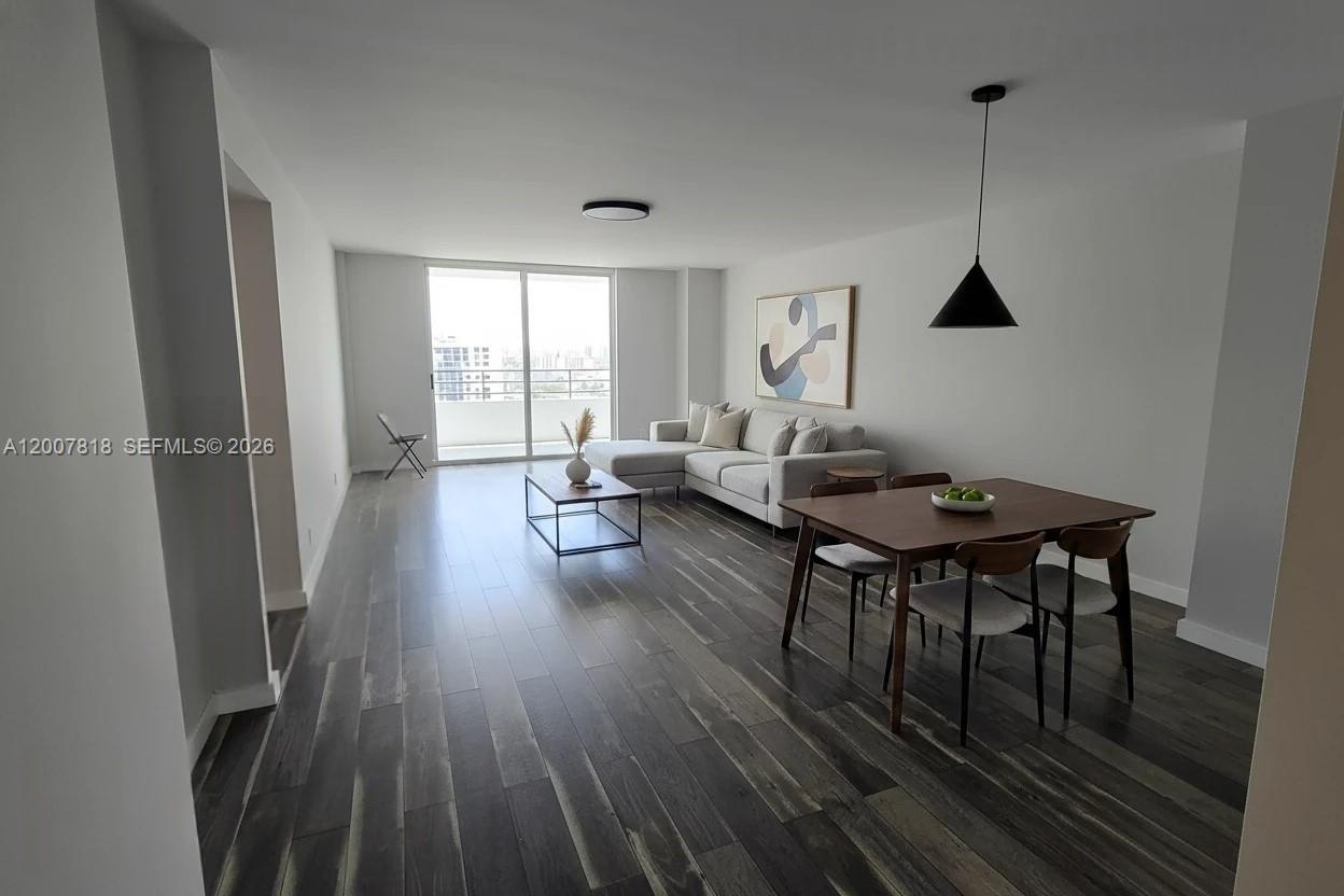 This living and dining area features dark wood-look flooring, a sectional sofa, and balcony access — 2500 Parkview Dr # 2317, Hallandale Beach FL 33009, HALLANDALE BEACH, FL