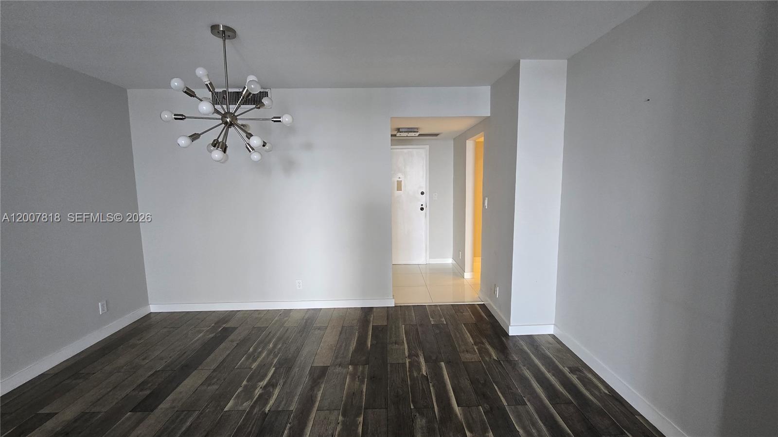 An empty room features gray walls, dark wood-look flooring, and a modern sputnik chandelier — 2500 Parkview Dr # 2317, Hallandale Beach FL 33009, HALLANDALE BEACH, FL