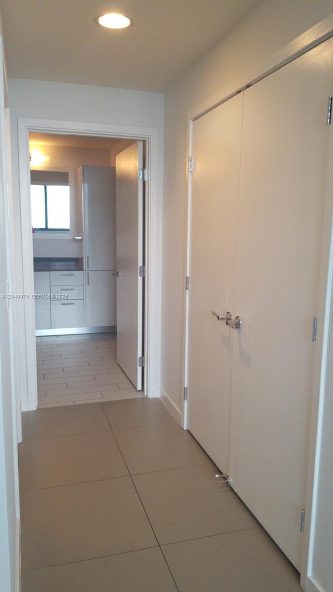 A hallway with large floor tiles leads to a kitchen featuring light-colored cabinetry — 999 SW 1st Ave # 3308, Miami FL 33130, MIAMI, FL