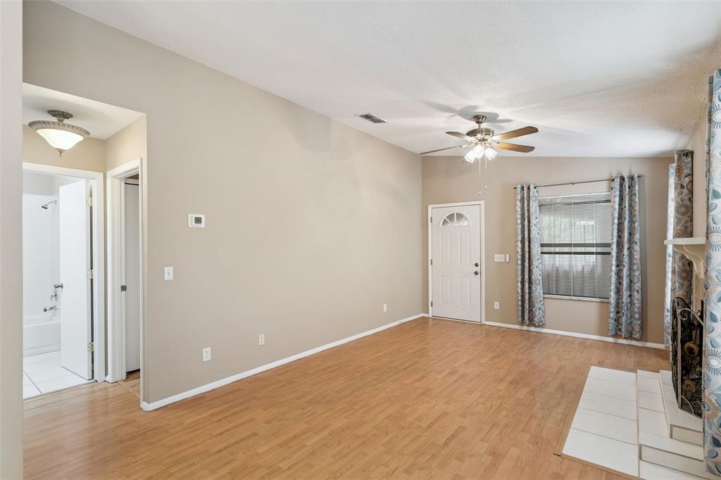 A living room with light wood flooring, a ceiling fan, a fireplace, and an entryway — 3148 S SEMORAN BLVD UNIT 705, ORLANDO, FL