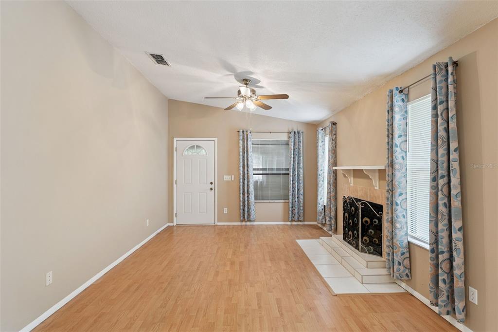 A living room with light wood flooring, a fireplace, and a ceiling fan — 3148 S SEMORAN BLVD UNIT 705, ORLANDO, FL