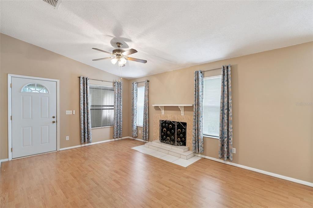 A living room features light wood-look flooring, a fireplace, and a ceiling fan — 3148 S SEMORAN BLVD UNIT 705, ORLANDO, FL