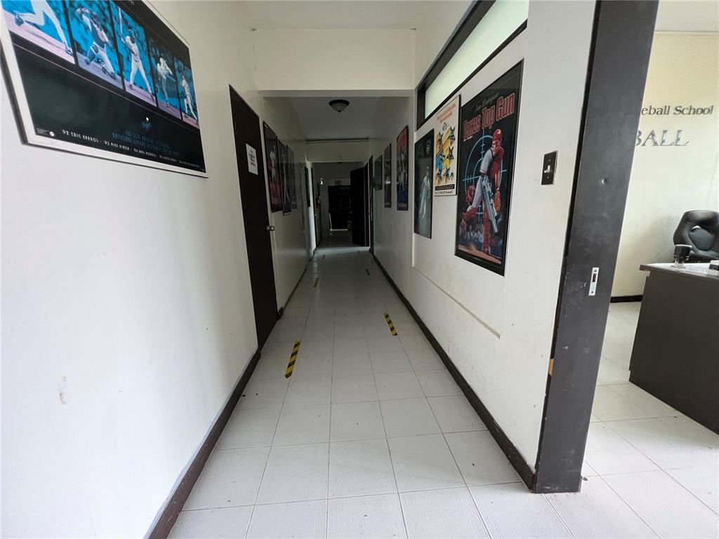 A hallway with white tiled floors and walls decorated with framed sports posters — Marginal PR-52 BARRIO MONTELLANOS, SECTOR PEPE HOYOS, CAYEY, PR