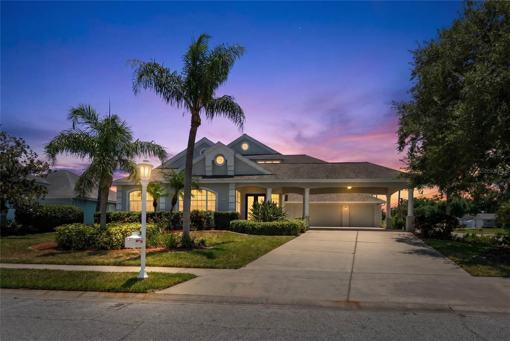 A single-story house with a covered driveway, palm trees, and a sunset sky — 4306 BARRACUDA DRIVE, BRADENTON, FL