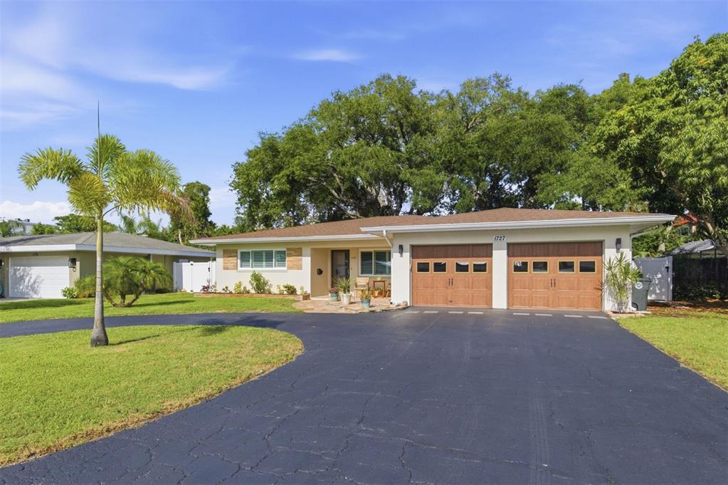 A single-story house features a two-car garage, a stone patio, and a large front lawn — 1727 CYPRESS AVENUE, BELLEAIR, FL