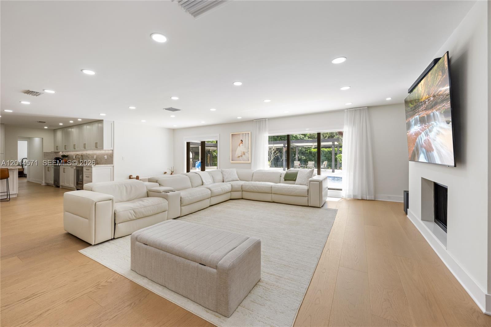 A spacious living room features a large white sectional, light wood floors, and a fireplace — 15110 N Saxon Cir, Southwest Ranches FL 33331, SOUTHWEST RANCHES, FL