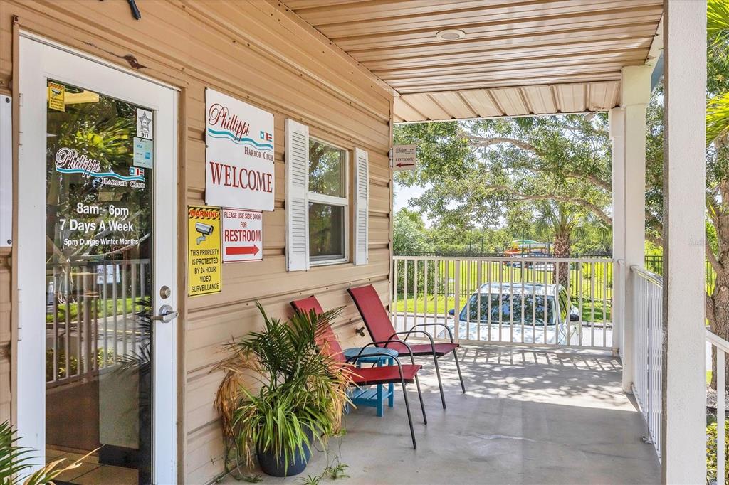A covered porch features two red lounge chairs, a potted plant, and a glass door — 1780 PHILLIPPI SHORES DRIVE UNIT E1-46, SARASOTA, FL