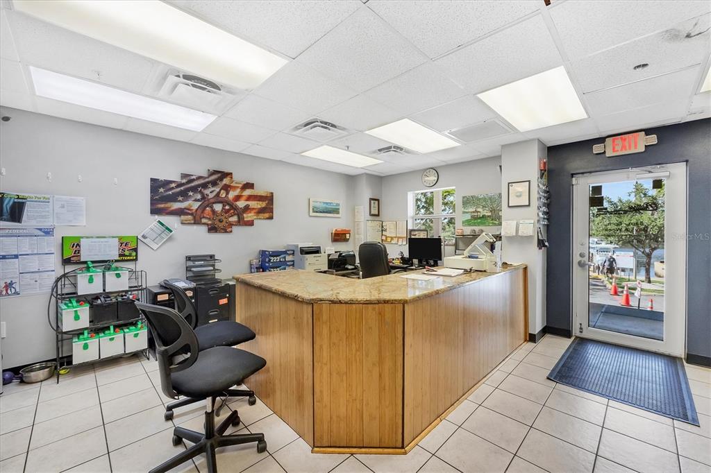 A commercial office reception area features a granite-topped wooden desk, tile flooring, and an exit door — 1780 PHILLIPPI SHORES DRIVE UNIT E1-46, SARASOTA, FL