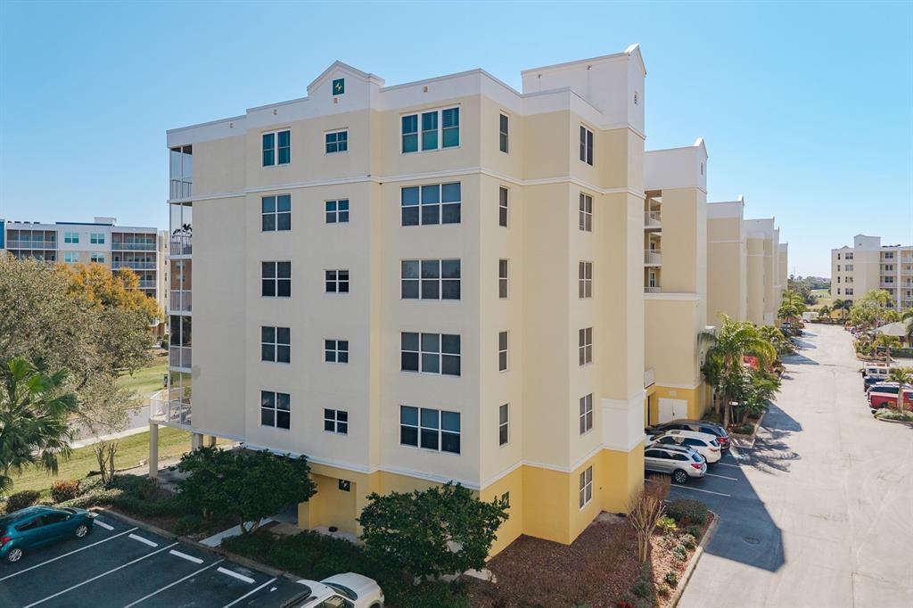 An exterior view of a multi-story yellow apartment building with a parking lot — 1200 COUNTRY CLUB DRIVE UNIT 4202, LARGO, FL
