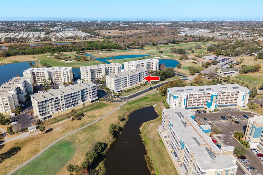 An aerial view shows several multi-story apartment buildings situated near a golf course and ponds — 1200 COUNTRY CLUB DRIVE UNIT 4202, LARGO, FL