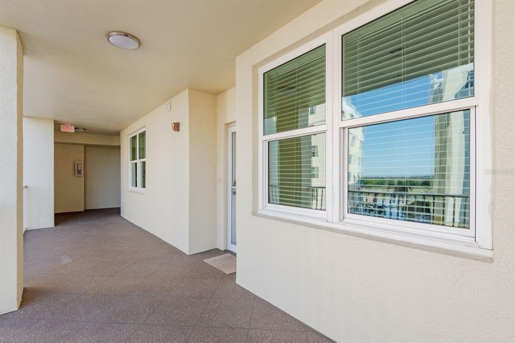 A covered outdoor walkway features light-colored walls, a textured floor, and a large window — 1200 COUNTRY CLUB DRIVE UNIT 4202, LARGO, FL