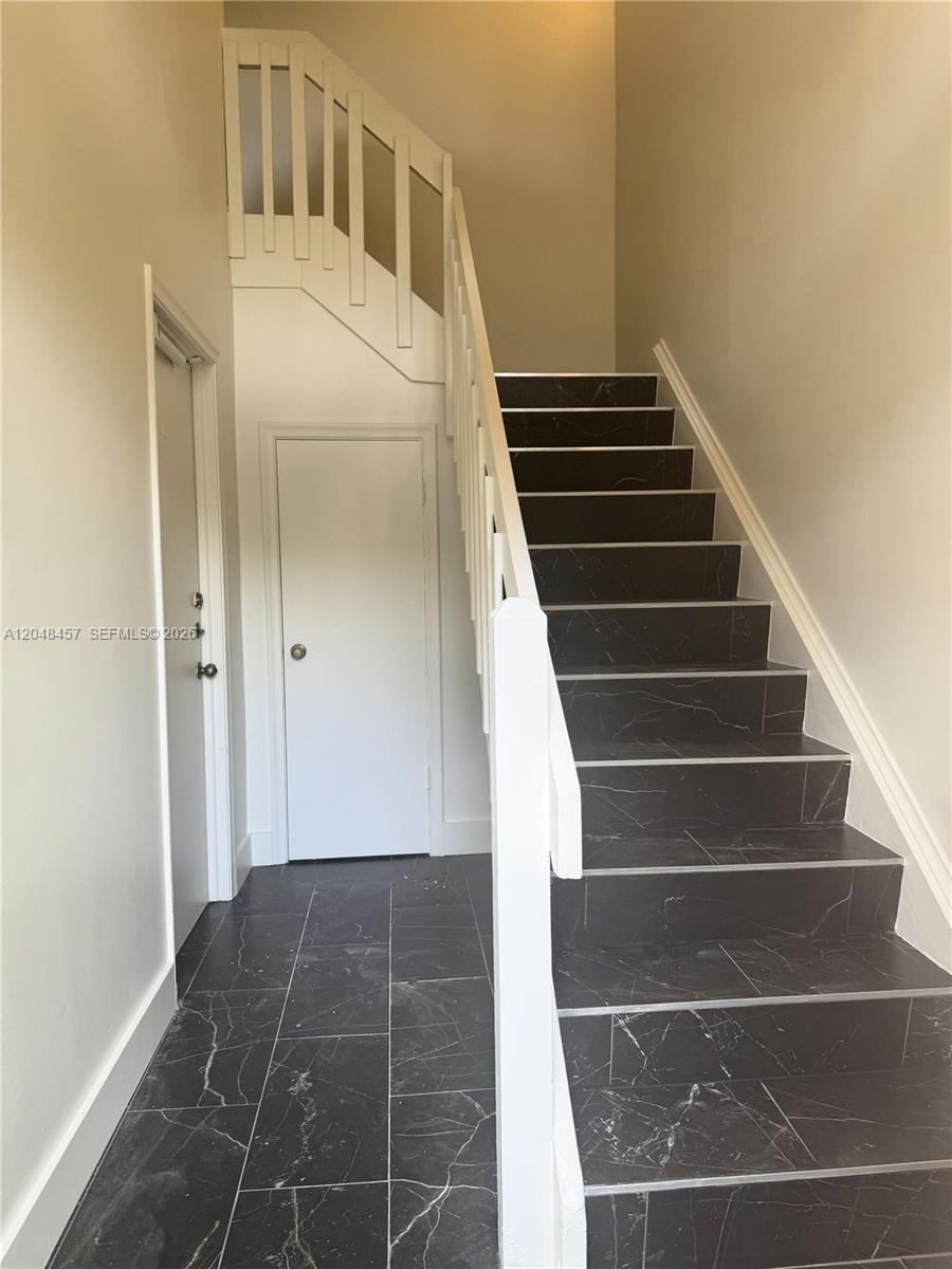 A staircase with black marble-look tile steps and white railings leads to an upper level — 11361 SW 109th Rd # 58D, Miami FL 33176, MIAMI, FL