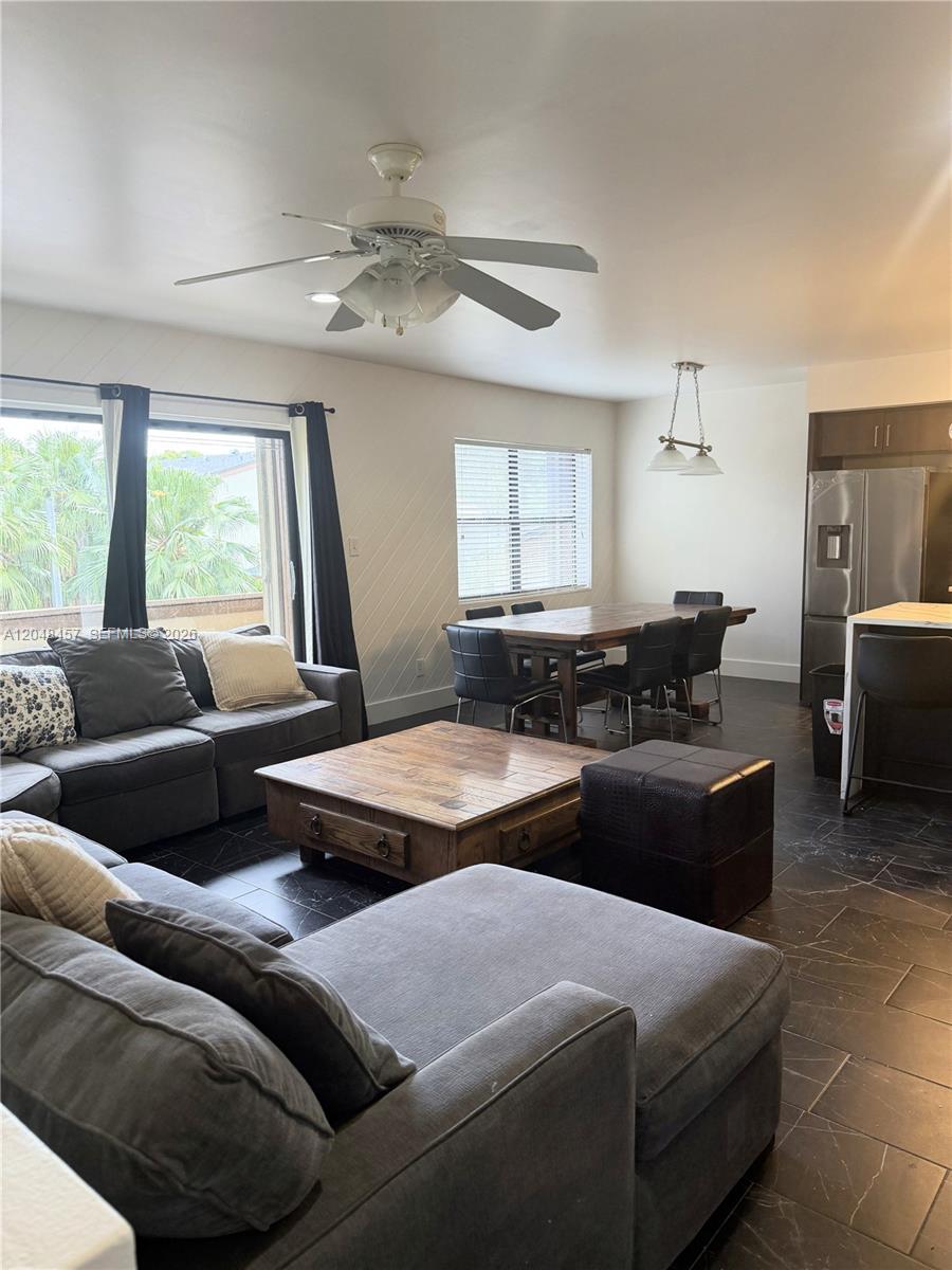An open-concept living and dining area features dark tile flooring, a sectional sofa, and furniture — 11361 SW 109th Rd # 58D, Miami FL 33176, MIAMI, FL