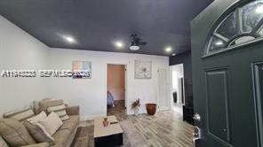A living room features light wood-look flooring, a dark ceiling, and a dark front door — 88 NE 68th Ter # 88, Miami FL 33138, MIAMI, FL