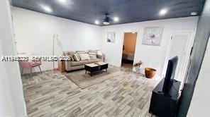 A living room with light wood-look flooring, a beige sofa, and a dark ceiling — 88 NE 68th Ter # 88, Miami FL 33138, MIAMI, FL