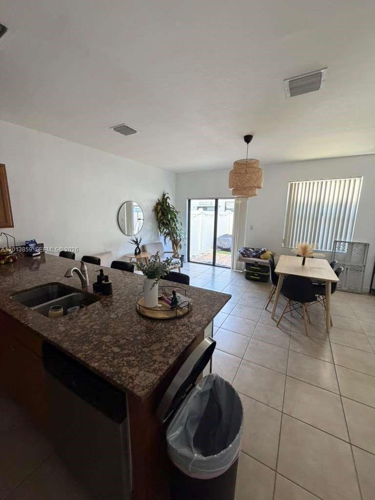 A kitchen with granite countertops overlooks a dining area and a living room with tile floors — 9337 W 33rd Way, Hialeah FL 33018, HIALEAH, FL
