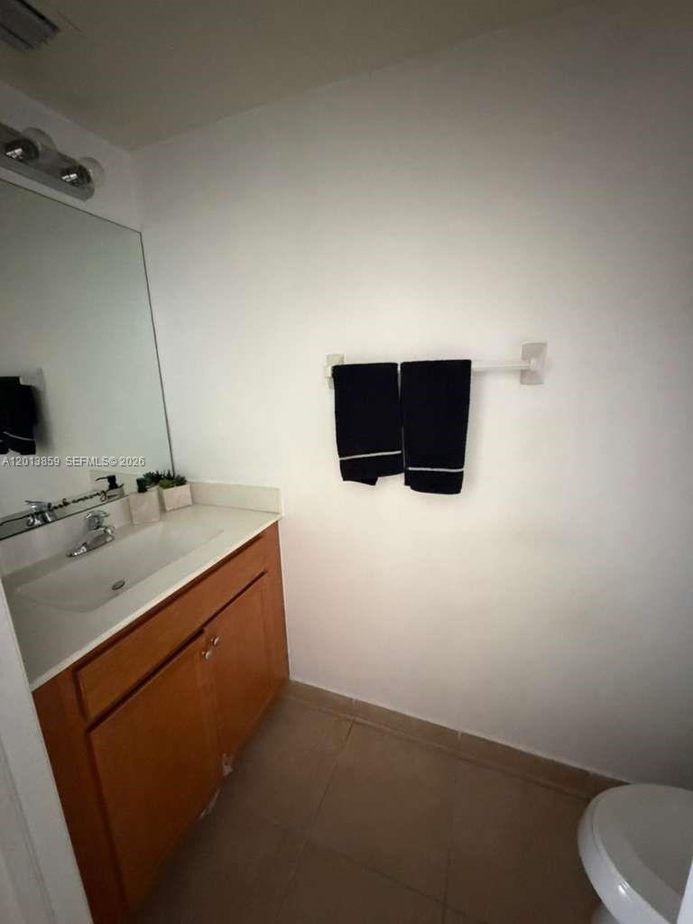A bathroom features a wooden vanity with a white sink, a mirror, and dark towels — 9337 W 33rd Way, Hialeah FL 33018, HIALEAH, FL