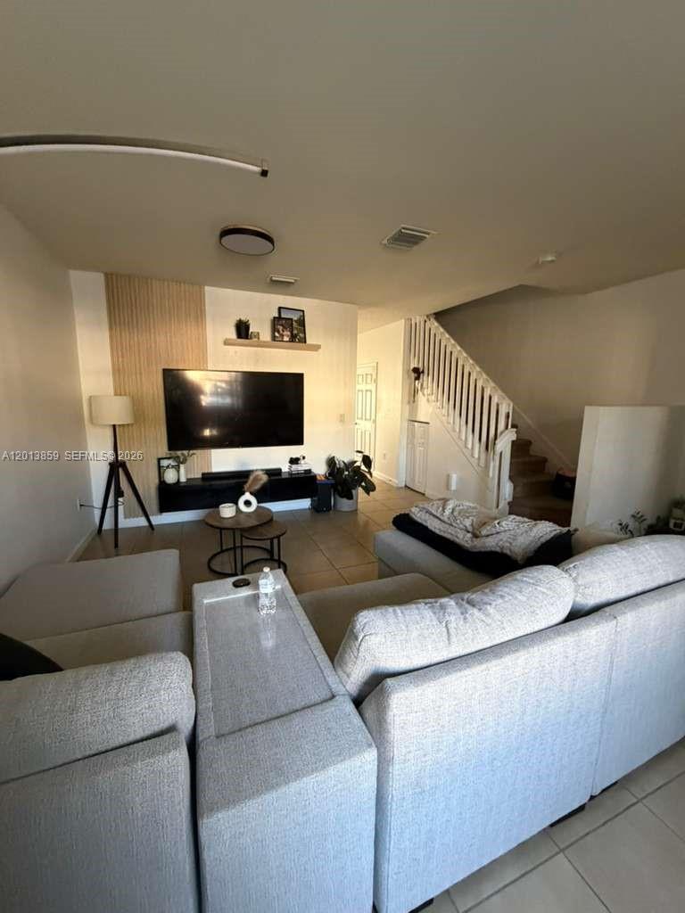 A living room features a large sectional sofa, a wall-mounted television, and a staircase — 9337 W 33rd Way, Hialeah FL 33018, HIALEAH, FL