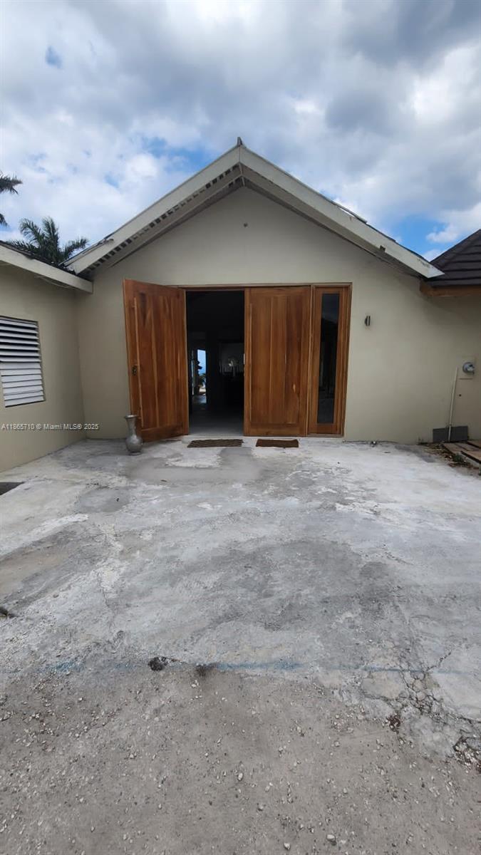 A concrete patio leads to a house entrance with large wooden double doors — 00 Villa,Montego Bay, Jamaica, NA, NA