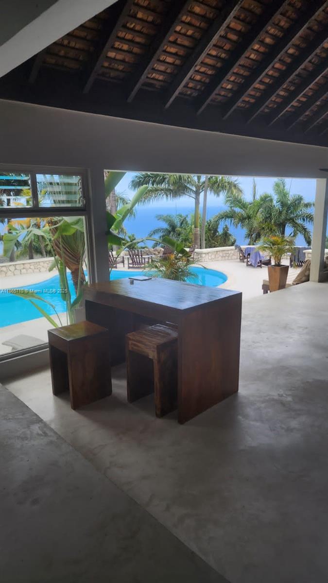 An open-air patio features a wooden table with stools overlooking a swimming pool and ocean — 00 Villa,Montego Bay, Jamaica, NA, NA