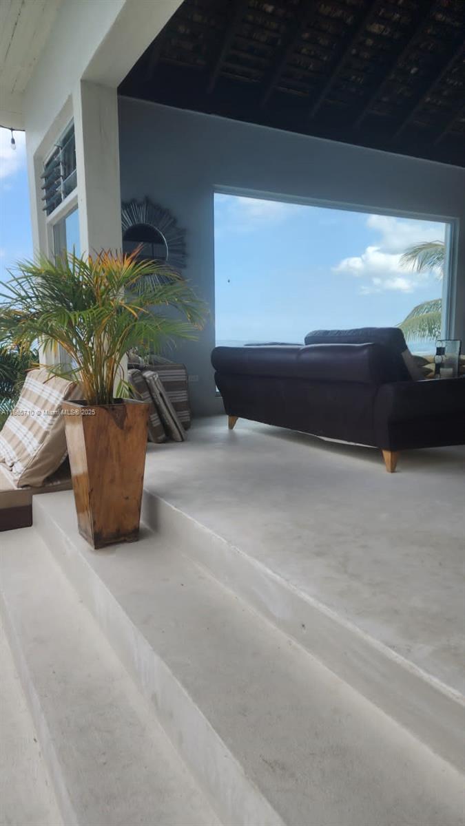 A living room with a dark sofa overlooks the ocean through a large window — 00 Villa,Montego Bay, Jamaica, NA, NA